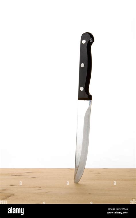 Kitchen knife stuck in a wooden table Stock Photo - Alamy