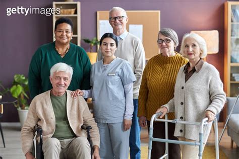 Senior People Looking At Camera In Retirement Home While Posing With