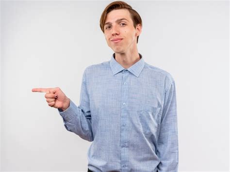 Hombre joven con camisa azul apuntando con el dedo índice hacia el lado