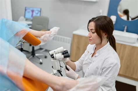 Joven doctora haciendo un examen ginecológico de una paciente en silla