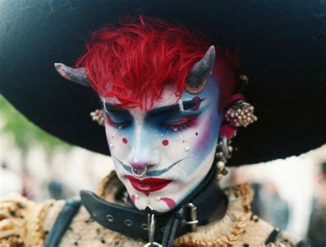 A Woman With Red Hair And Makeup Is Dressed Up As A Demon For The Day