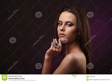 Beautiful Brunette Woman With Professional Makeup And Hairstyle Showing Big Ring And Earrings