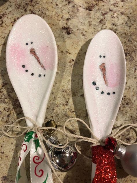 Two Spoons Decorated With Snowmen And Christmas Ornaments On A Counter