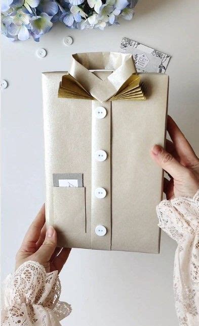 A Person Is Holding Up A Gift Wrapped In Brown Paper With Gold Bow Ties