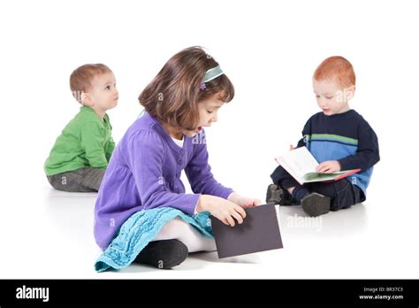 Three kids sitting on floor and reading books. Isolated on white with shadows Stock Photo - Alamy