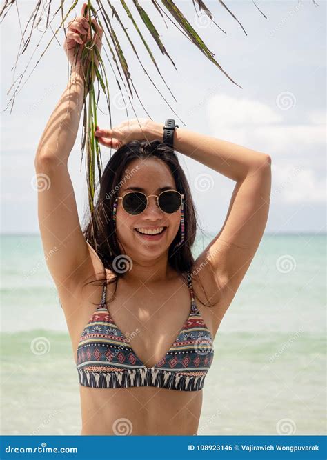 Asian Woman In Bikini Posture With Coconut Palm Leaf On Tropical Beach