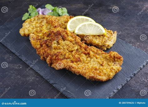 Traditional Deep Fried Schnitzel With Lemon Slices And Onion Rings On A