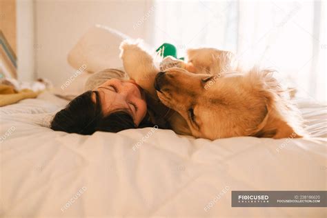 Chica Acostada En Una Cama Con Su Perro Recuperador De Oro En