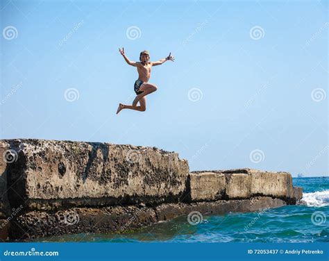 El Muchacho Que Salta Del Acantilado En El Mar Imagen De Archivo