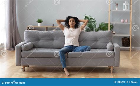 Calm Black Woman Relaxing On Comfortable Sofa In Living Room Stock