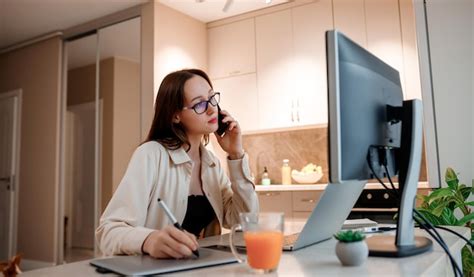 Empresária trabalhando em home office no laptop e falando ao telefone