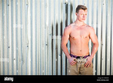 A 19 Year Old Teenage Boy Young Man Person Bare Chested Standing In Front Of Shiny Corrugated