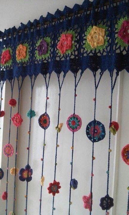 A Crocheted Curtain Hanging From The Side Of A Window With Flowers On It