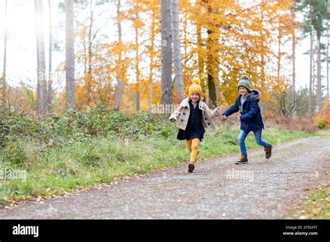 Cheerful Siblings Playing While Running On Forest Path Stock Photo Alamy