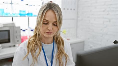 Focused Blonde Woman In A White Lab Coat Working In A Bright Laboratory