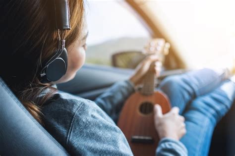 Premium Photo A Woman With Headphone Playing Ukulele While Riding In