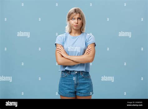 Femme blonde troublée et perplexe avec peau bronzée tenir les mains croisées sur la poitrine en