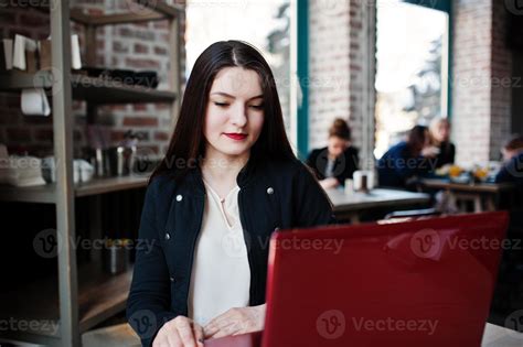 Brunette Girl Sitting On Cafe And Working With Red Laptop Stock Photo At Vecteezy