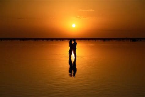 Premium Photo Couple With A Bouquet On A Pink Lake Sunset And Reflection In The Water