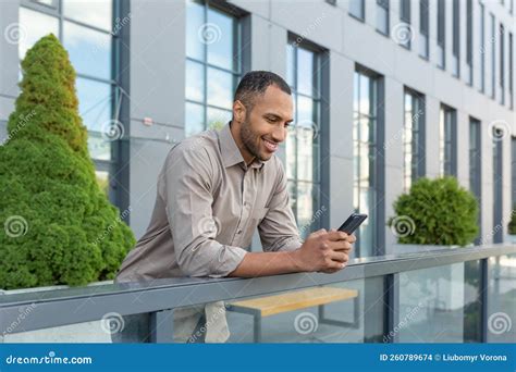 Hispanic Man Outside Modern Office Building Using Smartphone