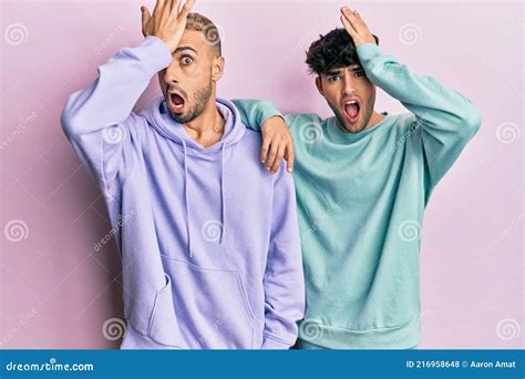 Homosexual Gay Couple Standing Together Wearing Casual Clothes Surprised With Hand On Head For