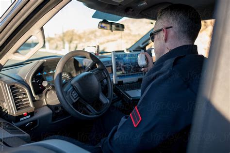 A Police Officer Uses A Radio While Sitting In A Police Vehicle Del Colaborador De Stocksy