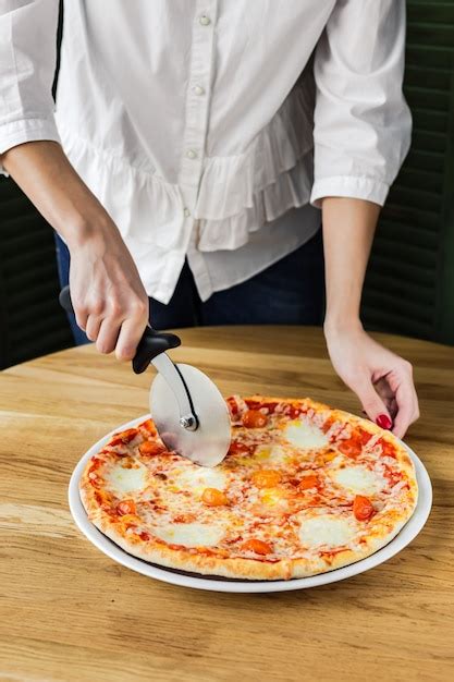 Premium Photo | Woman cutting pizza with a pizza cutter