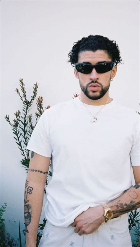 A Man With Tattoos And Sunglasses Standing In Front Of Plants