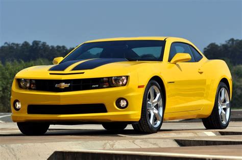 A Yellow Chevrolet Camaro Is Driving Down The Road