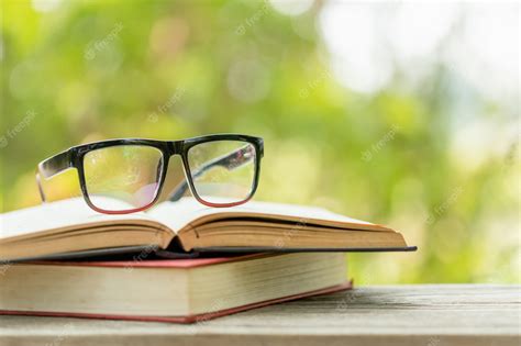 Premium Photo Book And Eye Glasses On Wooden Table With Abstract Green Nature Blur Reading And