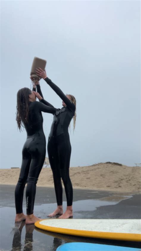 Two Women In Wetsuits Standing On Surfboards