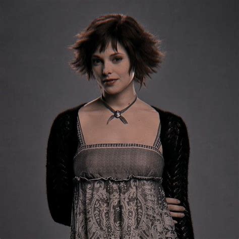 a woman with short hair wearing a dress and black cardigan over her shoulders, standing in front ...