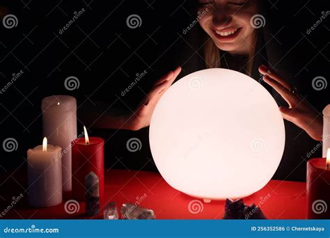 Soothsayer Using Glowing Crystal Ball To Predict Future At Table In