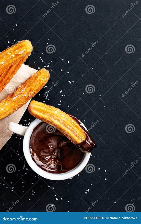 Churros With Sugar Dipped In Chocolate Sauce On A Black Background