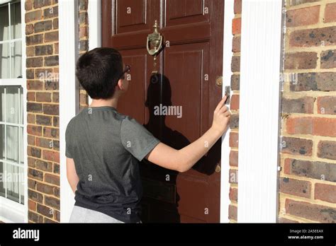 Child Ringing Doorbell On Front Door Number 3 Wearing Glasses Brown