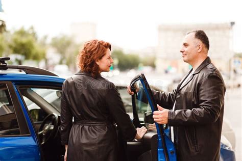 Middle Aged Man Helps A Woman Get Into The Car Stock Photo Image Of