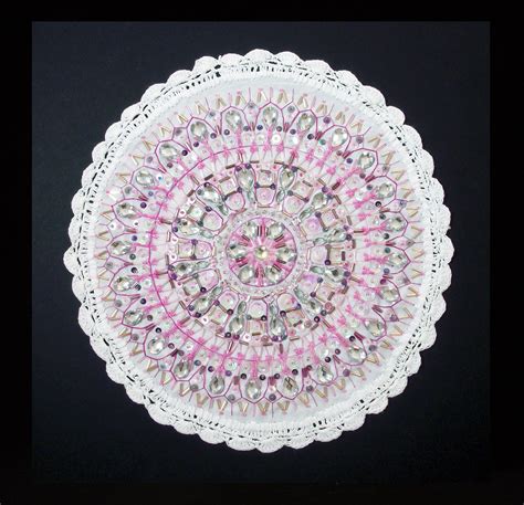 A White Doily With Pink And Silver Designs On The Edges Is Shown