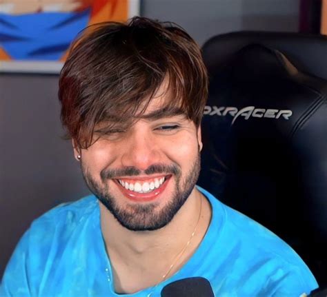 A Smiling Man Sitting In Front Of A Microphone And Wearing A Blue Shirt