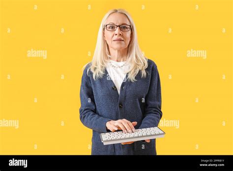 Mature Female Programmer With Computer Keyboard On Yellow Background