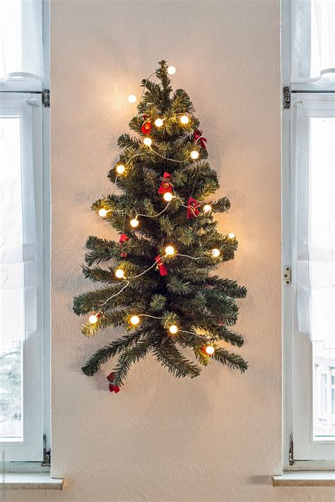 Decorated Artificial Christmas Tree Hangs On A Wall Between Two