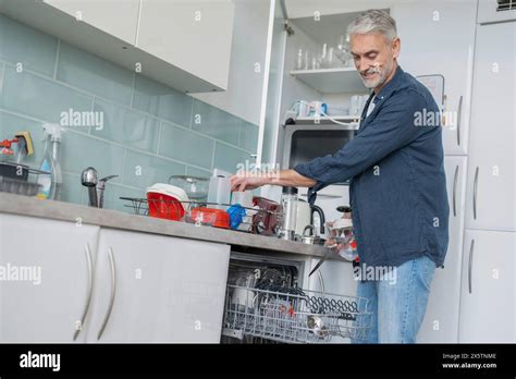 Smiling Mature Man Loading Dishwasher At Home Stock Photo Alamy