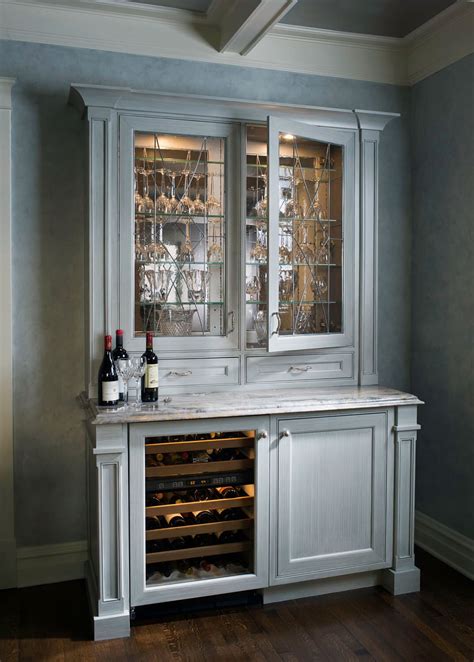 A Standalone Cabinet In White Stained Carved Wood Holds Glassware