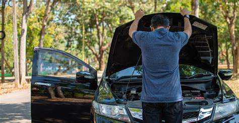 Man stands and inspects a broken-down car in a rural suburban forest ...