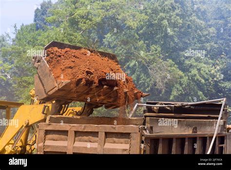 Una excavadora está cargando tierra en un camión de descarga que es un