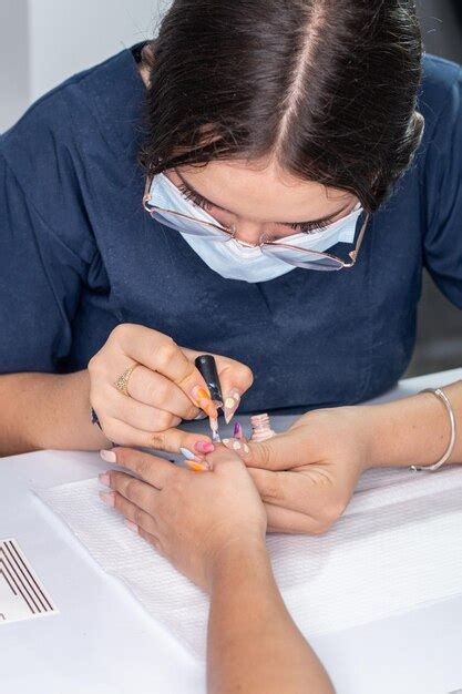 Foto Vertical De Manicurista Profesional Aplicando Esmalte Color Piel