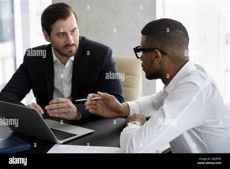 Two Diverse Businessmen Negotiating In Modern Office During Meeting