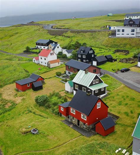 an aerial view of several houses in the countryside with green grass and ocean in the background