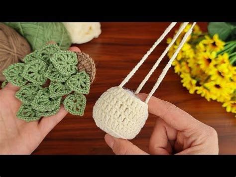 Two Hands Holding Small Crocheted Balls Of Yarn Next To Yellow And