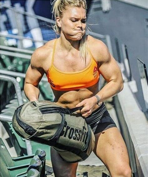 A Woman In An Orange Sports Bra Top And Black Shorts Is Posing For The Camera