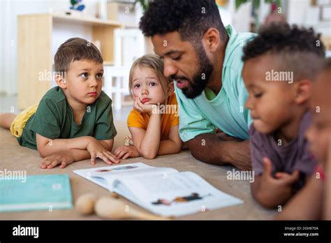 Group Of Small Nursery School Children With Man Teacher On Floor